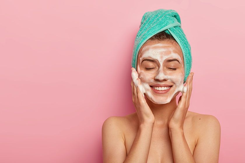 9 Common Mistakes to Avoid When Choosing a Face Cream for Women 1 women washes face with cleansing gel has soap complexion keeps eyes shut wears wrapped towel