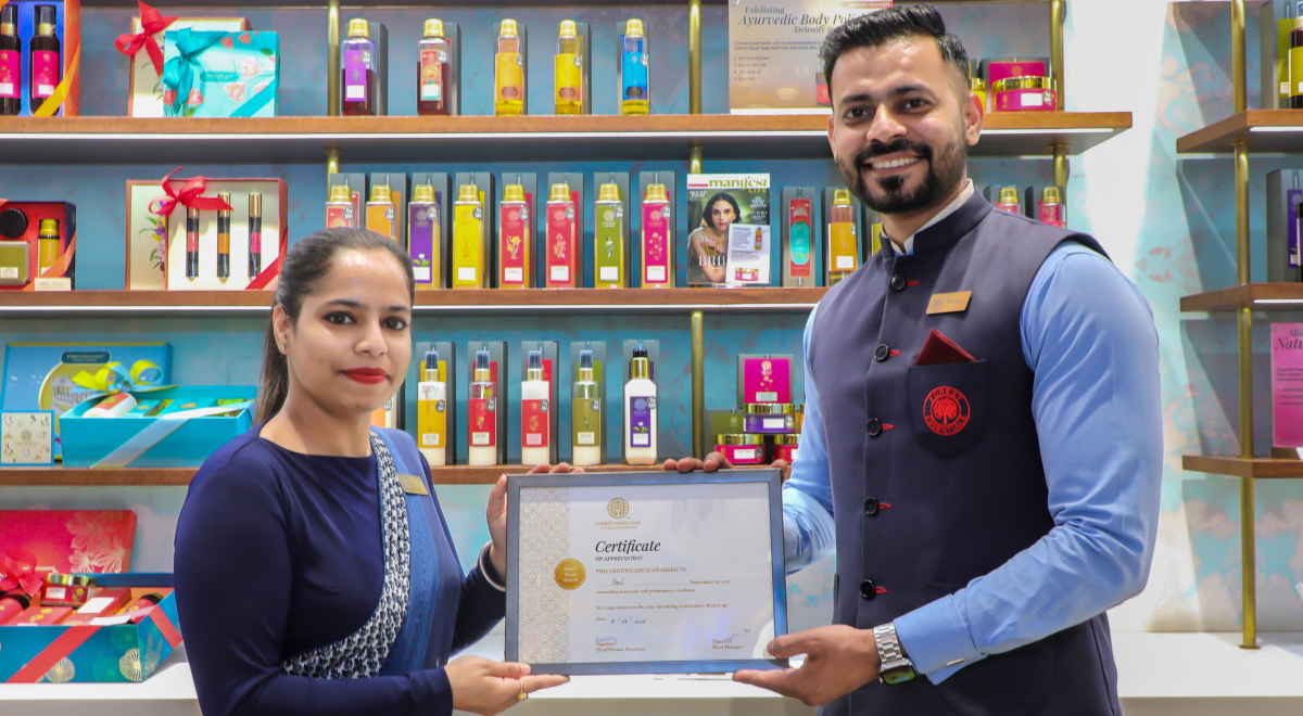 Two people holding a certificate in a colorful store with shelves of products behind them